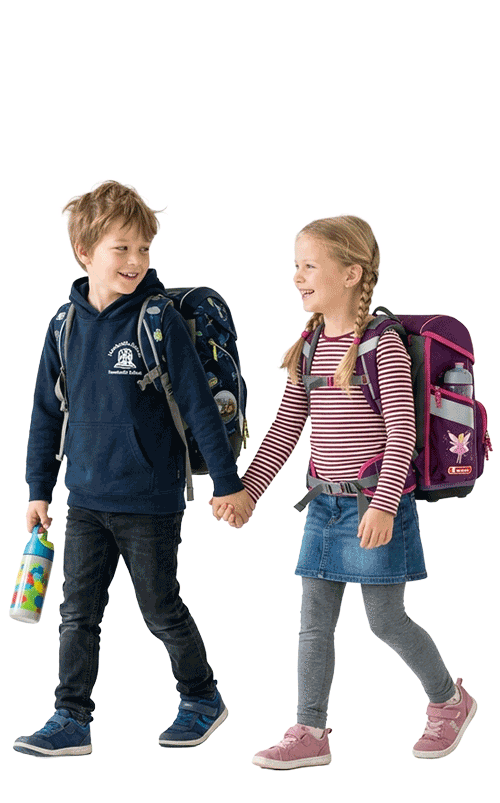 Junge und Mädchen im Grundschulalter mit Schulranzen laufen gemeinsam zur Schule, halten sich an den Händen und wirken fröhlich und entspannt, sie freuen sich auf den Schulstart an der Grundschule Ranis