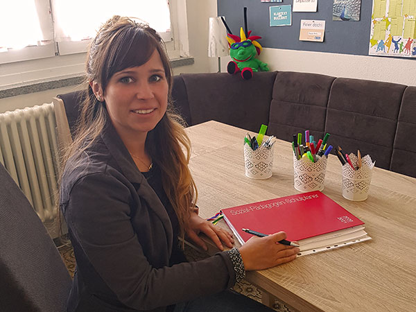 Schulsozialarbeiterin Julia Walther sitzt an einem Tisch im Beratungsraum der Schule, umgeben von Stiften und Unterlagen, Ansprechpartnerin für Unterstützung und Beratung im Schulalltag.